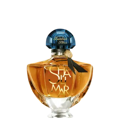 Frasco de perfume Guerlain Paris com tampa de cristal azul e rótulo dourado com a inscrição "Shalimar". Embalagem de vidro âmbar com design elegante e clássico.
