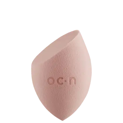 Esponjas de maquiagem, com formato assimétrico e textura macia, com o logotipo "O.C.N." impresso na superfície.