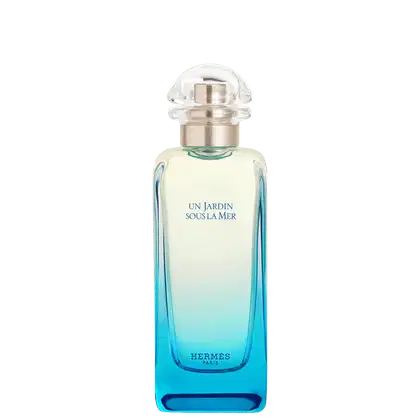 Frasco de perfume Hermès com design elegante e moderno. Recipiente de vidro transparente com degradê de azul, rótulo branco com texto em azul "Un Jardin Sous La Mer". Tampa de metal prateado com design arredondado.