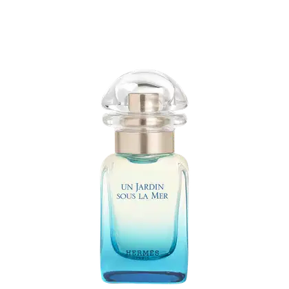 Frasco de perfume Hermès "Un Jardin Sous La Mer", com tampa de vidro e detalhes em dourado, contendo líquido azul claro. Rótulo com o nome do produto e marca em destaque.