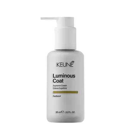 Frasco branco com bomba doseadora contendo o produto Luminous Coat da Keune, um creme supremo com pantenol. O rótulo em preto e dourado destaca o nome da marca e o nome do produto.