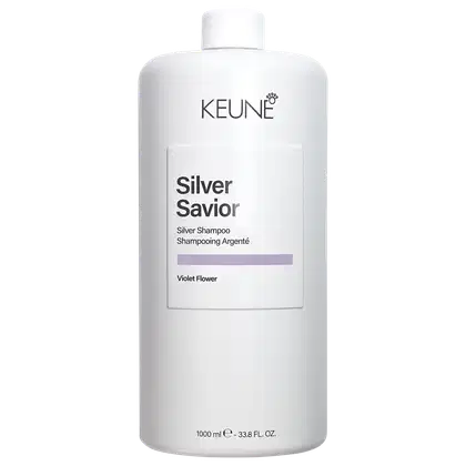 Frasco branco da linha Silver Savior da Keune, contendo shampoo prateado com aroma de flor violeta. Rótulo com nome da marca e produto em destaque.
