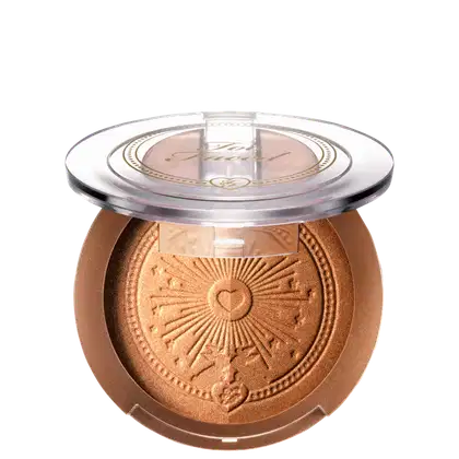 Pó bronzeador compacto em embalagem redonda de plástico transparente, com detalhes dourados e um desenho de sol estampado no centro. O produto possui uma tonalidade dourada brilhante.