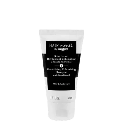 Frasco branco com rótulo preto e branco da marca Sisley, contendo "Soin Lavant Revitalisant Volumateur à l'huile de Camélia", um shampoo revitalizante e volumizador com óleo de camélia.