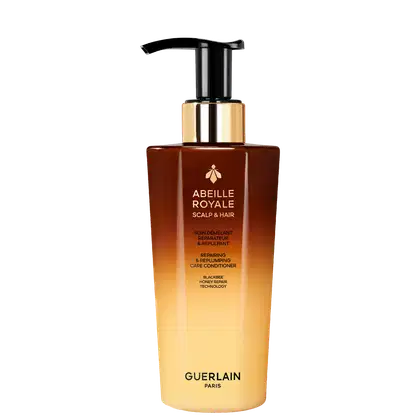 Frasco de condicionador Abeille Royale da Guerlain, com design elegante em tons de marrom e dourado. Apresenta bomba doseadora preta e rótulo com informações sobre os benefícios do produto para o couro cabeludo e cabelos.