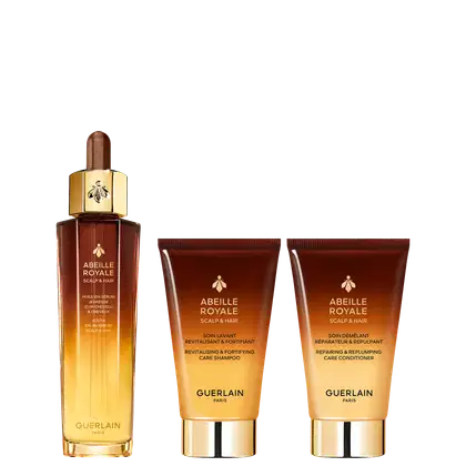 Conjunto de produtos Guerlain Abeille Royale para cuidados com o couro cabeludo e cabelos, incluindo um sérum em frasco dourado, um xampu revitalizante e um condicionador reparador em embalagens no tom de marrom.