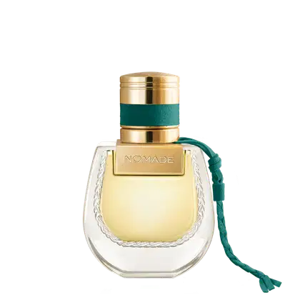Frasco de perfume dourado com tampa e faixa verde, rótulo com a marca "NOMADE", embalagem de vidro com detalhes em relevo.