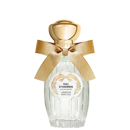 Eau de Parfum Eau d'Hadrien da Annick Goutal em frasco de cristal estriado com tampa dourada em formato de esfera. Decorado com laço de fita bege e rótulo circular branco com detalhes florais dourados.