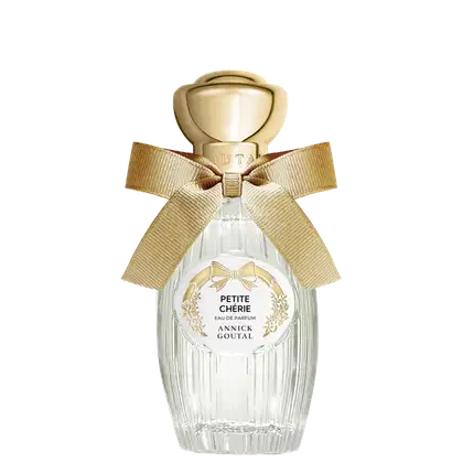 Eau de Parfum Petite Chérie da Annick Goutal em frasco de cristal com tampa dourada em formato de cúpula. Embalagem decorada com laço de fita bege e rótulo circular com detalhes florais dourados.