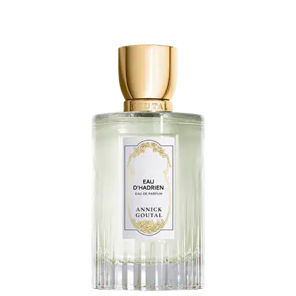 Eau de Parfum Eau d'Hadrien da Annick Goutal em frasco cilíndrico de vidro transparente com líquido incolor. Tampa dourada cilíndrica. Rótulo branco com ornamentação dourada e texto em preto.