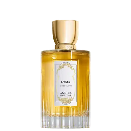 Eau de Parfum Sables da Annick Goutal em frasco cilíndrico de vidro com líquido amarelo dourado. Tampa dourada polida. Rótulo branco com ornamentação dourada e texto em preto. Base estriada em vidro transparente.
