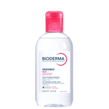 Frasco de água micelar da marca Bioderma, da linha Sensibio H2O, para peles sensíveis. Embalagem de plástico transparente com tampa rosada, contendo 250 ml do produto.