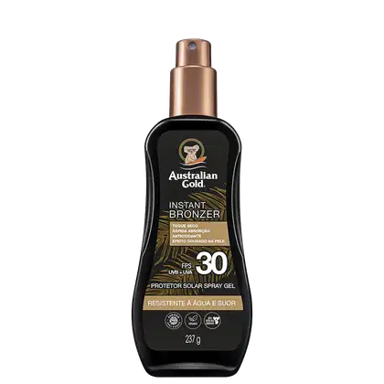 Embalagem âmbar com detalhes dourados, formato de frasco spray. Rótulo indica "Instant Bronzer", fator de proteção solar FPS 30, resistente à água e suor. Apresenta o logotipo da marca com um coala.