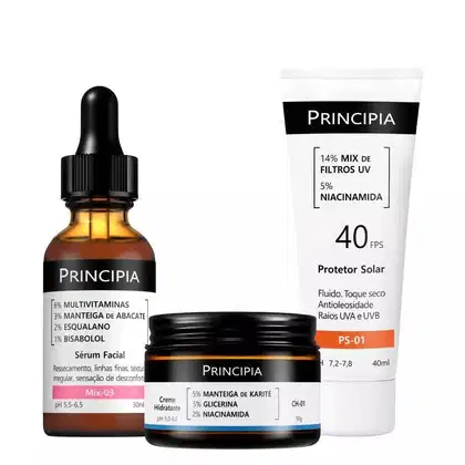 Três produtos da marca Principia: um sérum facial em frasco conta-gotas, um creme hidratante em pote e um protetor solar em tubo, com rótulos e informações sobre os ingredientes e propriedades dos produtos.