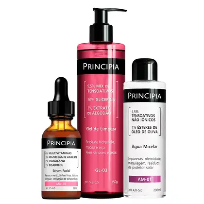 Três produtos da marca Principia: um sérum facial em frasco de vidro, um gel de limpeza em embalagem rosa e branca, e uma água micelar em frasco branco. Todos os produtos apresentam rótulos com informações sobre os ingredientes e benefícios.