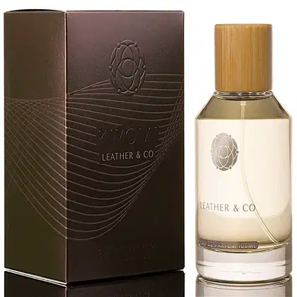 Caixa marrom escura com detalhes em relevo e logotipo do nome do perfume "Leather & Co." Frasco de perfume com tampa de bambu e rótulo com o mesmo nome da marca.