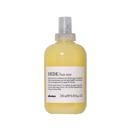 Frasco de spray amarelo da linha Dede da Davines, contendo um condicionador leave-in para todos os tipos de cabelo. O rótulo apresenta o nome do produto, "hair mist", e informações sobre os ingredientes e origem.