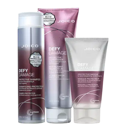 Produtos da linha Defy Damage da Joico, incluindo shampoo protetor, condicionador e máscara protetora, em embalagens de plástico e tubos com cores predominantes de branco e rosa.