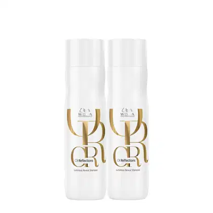 Dois shampoos da linha Oil Reflections da Wella Professionals, com rótulos dourados destacando o nome da linha e o tipo de produto: "Luminous Reveal Shampoo".