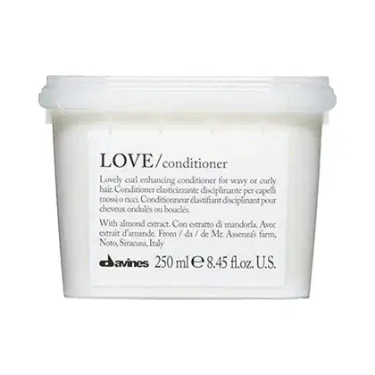 Frasco branco de condicionador Davines Love, com rótulo preto e branco descrevendo o produto como um condicionador para cabelos ondulados ou cacheados, com extrato de amêndoa.