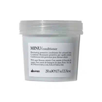 Frasco de condicionador Davines MINU, com 250 ml, embalagem transparente e rótulo branco com informações sobre o produto, que é um condicionador protetor iluminador para cabelos coloridos.