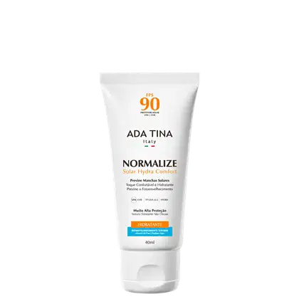 Tubo branco de protetor solar da marca Ada Tina, com rótulo em italiano indicando FPS 90 e o nome "Normalize Solar Hydra Comfort". O produto é descrito como hidratante e com alta proteção solar.