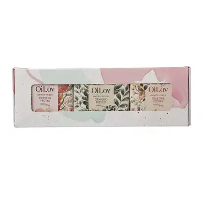 Caixa de presente contendo três sabonetes da marca OiLov. A embalagem apresenta uma estampa floral em tons de verde, rosa e branco.