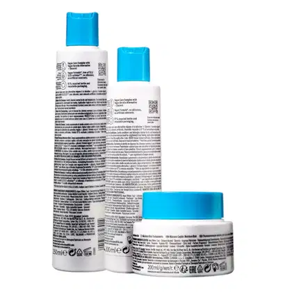 Três produtos da linha Bonacure da Schwarzkopf Professional: shampoo, condicionador e máscara de tratamento, em embalagens brancas e azuis, com rótulos indicando os nomes e benefícios dos produtos.