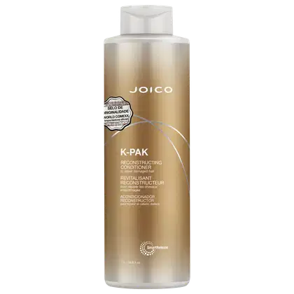 Frasco de condicionador de 1 Litro da marca Joico, da linha K-Pak, com embalagem em tons dourados e brancos. O rótulo destaca o "Selo de Originalidade World Comexx" e a função de reconstrução do produto.