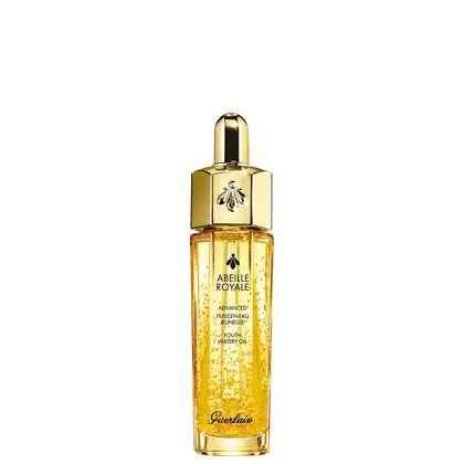 A imagem mostra o frasco do óleo hidratante Abeille Royale da Guerlain. É um frasco de vidro transparente contendo um líquido dourado brilhante, tem um formato cilíndrico alongado com uma tampa dourada na parte superior, com uma abelha estampada.