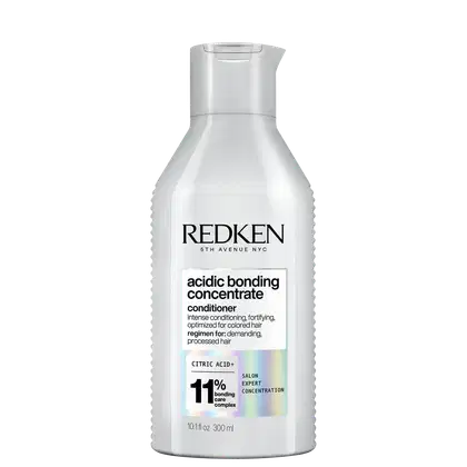 Frasco branco com rótulo da marca Redken. O rótulo apresenta o nome "Acidic Bonding Concentrate" e informações sobre o produto, como "intense conditioning, fortifying, optimized for colored hair". O frasco possui um design cilíndrico com tampa.