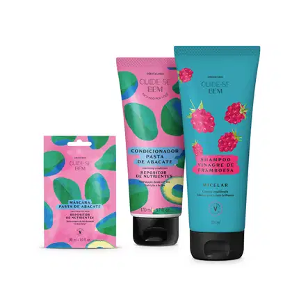 Três itens Cuide-se Bem Feira: sachê roxo com abacates ilustrados de máscara capilar Pasta de Abacate e dois frascos azuis, um com framboesas ilustradas de shampoo Vinagre de Framboesa e outro com coco ilustrados de condicionador Óleo de Coco.