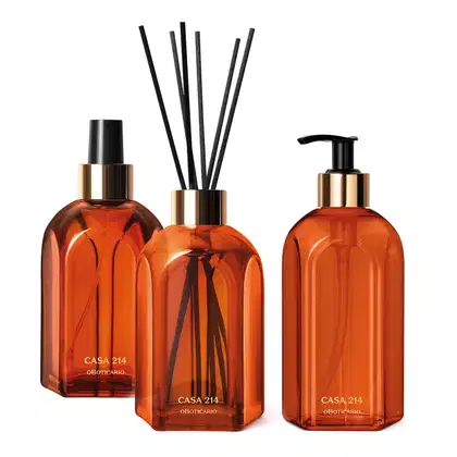Três vidros na cor laranja da marca Casa 214 Vanilla Sublime: difusor de ambientes com varetas, aromatizador de ambientes em spray e sabonete líquido com bomba dosadora preta.