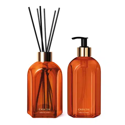 Dois vidros laranjas da marca Casa 214 Vanilla Sublime: um difusor de ambientes com varetas e um sabonete líquido com bico dosador preto.