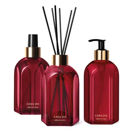 Três vidros vermelhos da marca Casa 214 Gardênia Imperial: um difusor de ambientes com varetas, um sabonete líquido com bico dosador preto e um aromatizador de ambientes com válvula spray preta.