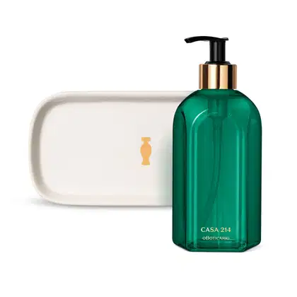 Vidro verde com detalhe dourado e tampa dosadora preta contendo 400ml de sabonete líquido Casa 214 Brisa de Cedro e uma bandeja de lavabo branca com logo da marca O Boticário em dourado.