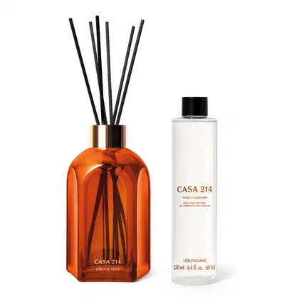 Imagem de dois produtos da marca Casa 214: sendo um frasco de vidro laranja com detalhe dourado e varetas pretas, e um refil para difusor de ambientes em frasco branco com rótulo "Vanilla Sublime".