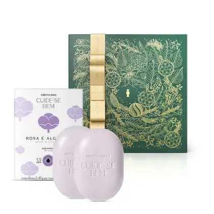 Imagem de dois sabonetes brancos com a marca Cuide-se Bem gravada no produto e sua caixa branca que traz ilustração de flores azuis com a linha Rosa e Algodão em letras pretas, além de uma caixa presenteável verde com fita e estampa douradas.
