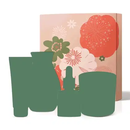 Imagem mostra uma caixa de presente rosa com flores estampadas e somente a silhueta de produtos de cuidados pessoais na cor cinza, sugerindo se tratar de um kit misterioso, com produtos diversificados. Um dos produtos pisca, mostrando um item Nativa SPA.