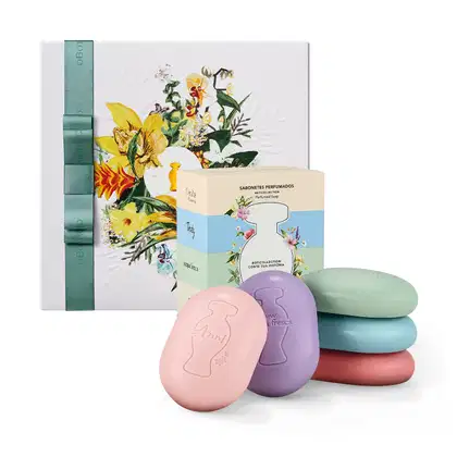 Caixa de presente com sabonetes perfumados em formatos de ovos coloridos, embalados em caixa com ilustração floral. Conjunto de sabonetes em tons pastel de rosa, roxo, azul e vermelho.