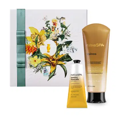 Caixa quadrada branca decorada com flores coloridas em tons de amarelo e verde e um laço verde na lateral. Em frente a ela, frasco de loção corporal e bisnaga de creme para mãos da marca Nativa SPA Quinoa em degradê de amarelo para o branco e tampa preta.