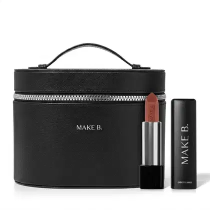 Frasqueira de maquiagem preta com zíper e alça, com aspecto rígido e estruturado feita em tecido tipo couro e logo Make B. em hot stamping prata e um batom vermelho aberto com a bala visivel, corpo prateado e base preta com tampa preta ao lado.