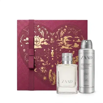 Caixa de presente de cor vinho com um grande coração contendo ilustrações em relevo de temática celestial. Ao lado, um frasco de item de perfumaria da marca Zaad e recipiente de desodorante aerossol da mesma marca.
