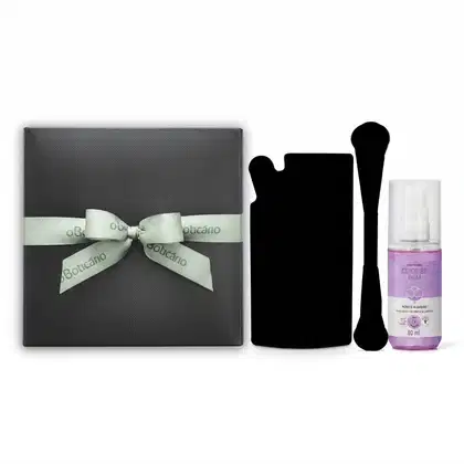 Caixa cinza com laço verde-claro da marca O Boticário, contendo um  Body Splash Desodorante Colônia Cuide-se Bem Rosa e Algodão e dois itens surpresas, cuja silhueta aparece em preto ao lado dos demais itens.