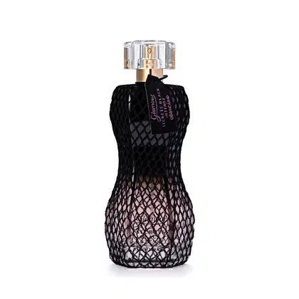 Perfume em frasco de vidro vestido com um tecido texturizado com padrão rendado. O frasco tem formato de torso feminino. O topo é transparente com detalhes dourados.