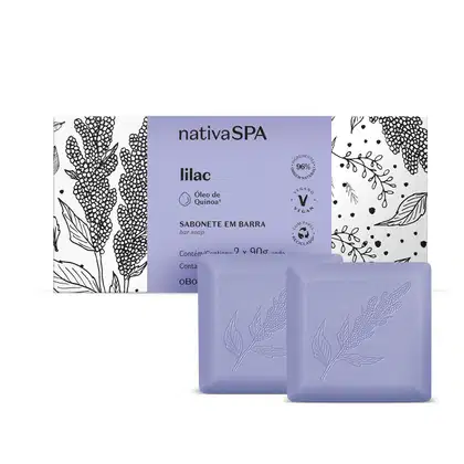 Caixa branca com faixa lilás e ilustrações na cor preta ao lado de dois sabonetes em barra quadrados na cor lilás da marca Nativa SPA Lilac, contendo 90g cada um.