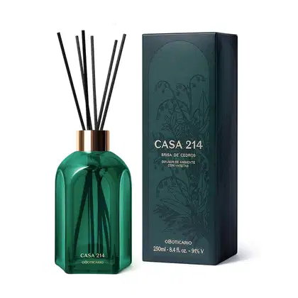 Difusor de ambientes em vidro verde com varetas e letras douradas da marca Casa 214 Brisa de Cedro com a caixa verde e dourada ao lado.
