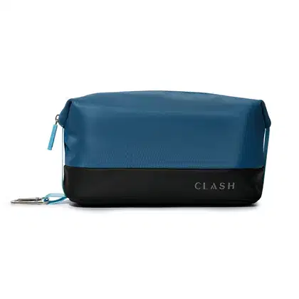 Bolsa de cosméticos azul-marinho com faixa preta na barra, com zíper e alça, exibindo a marca "CLASH" em letras grandes no canto inferior direito.