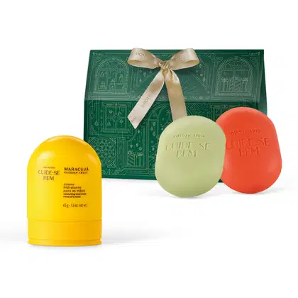 A imagem mostra produtos da linha Cuide-se Bem Feira: inclui um creme hidratante amarelo em um frasco cilíndrico, um sabonete oval verde e um sabonete oval vermelho. Traz ainda uma caixa verde com uma fita dourada