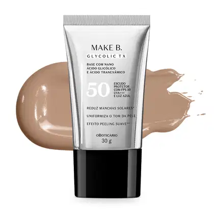A imagem mostra um tubo de base líquida Make B. Glycolic TX. Ele é prateado, possui tampa preta e informações em letras pretas. Atrás da embalagem está a textura do produto, mostrando sua intensidade e a real cor da base.